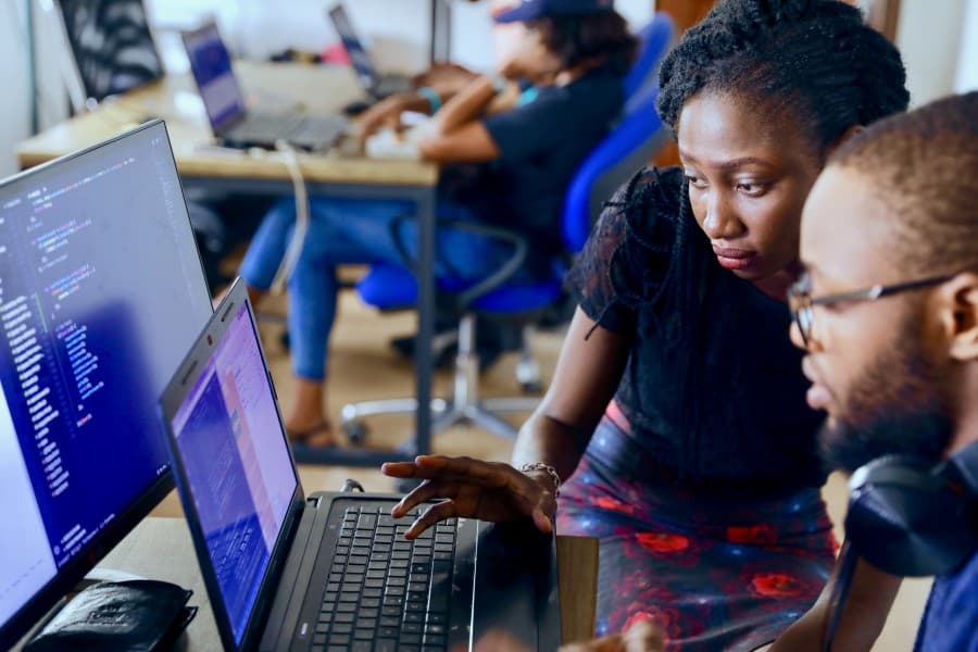 People collaborating at a desk with laptops